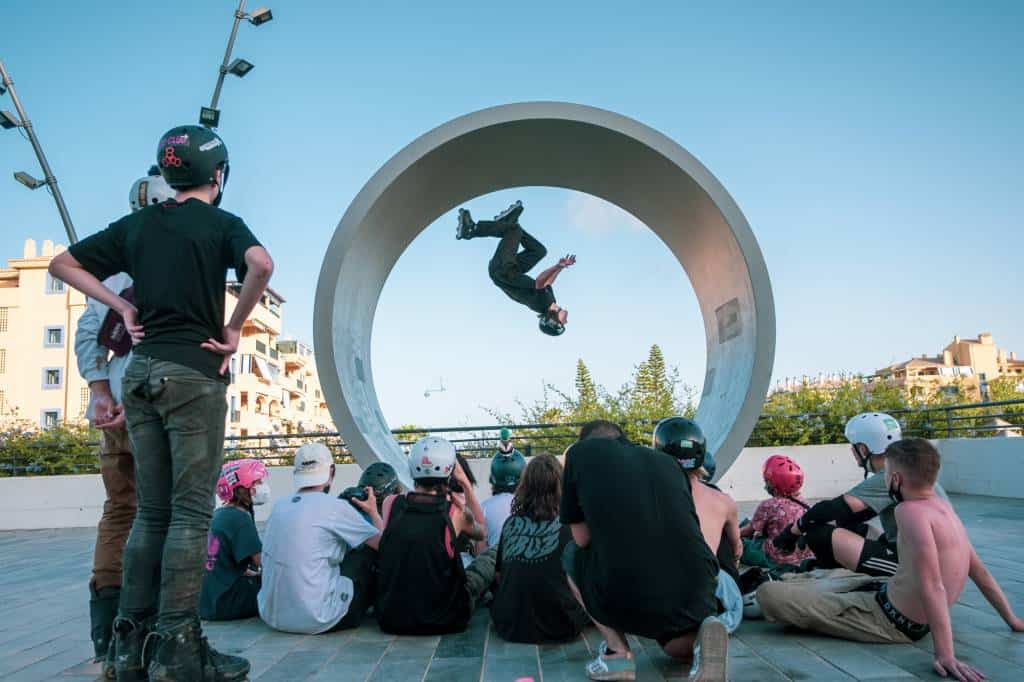 A skater flips through the giant ring sculpture in San Pedro while campers watch