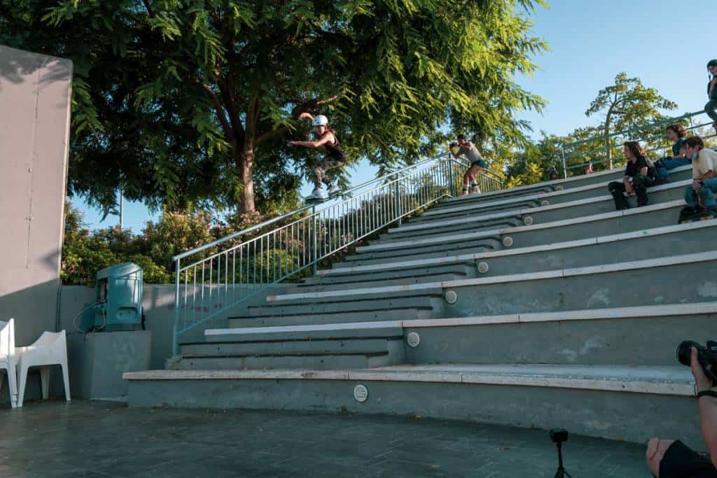 A skater launching off the steps of an amphitheatre under the trees