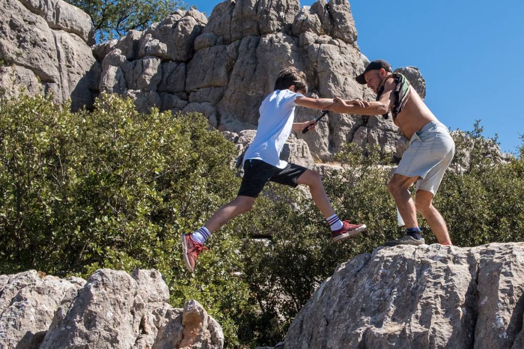 Two campers helping each other climb the limestone rocks of El Torcal