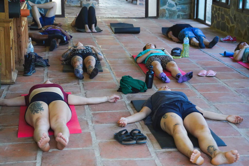 Campers lying on mats on a tiled terrace during a stretching session