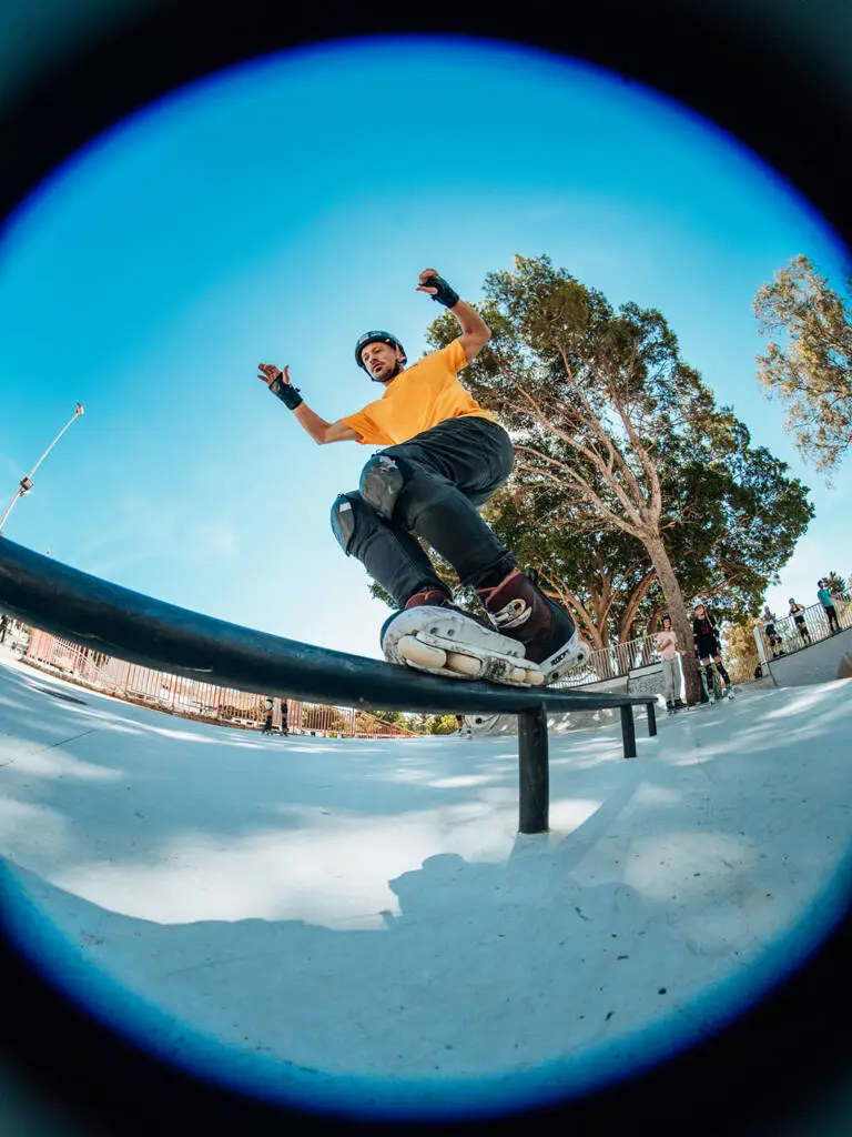 Inline skater grinding a rail against a blue sky