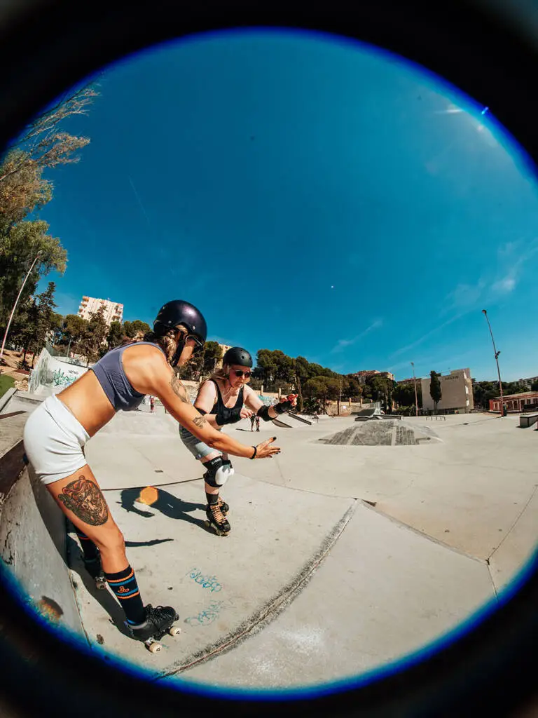 Skaters at an outdoor park with the city behind