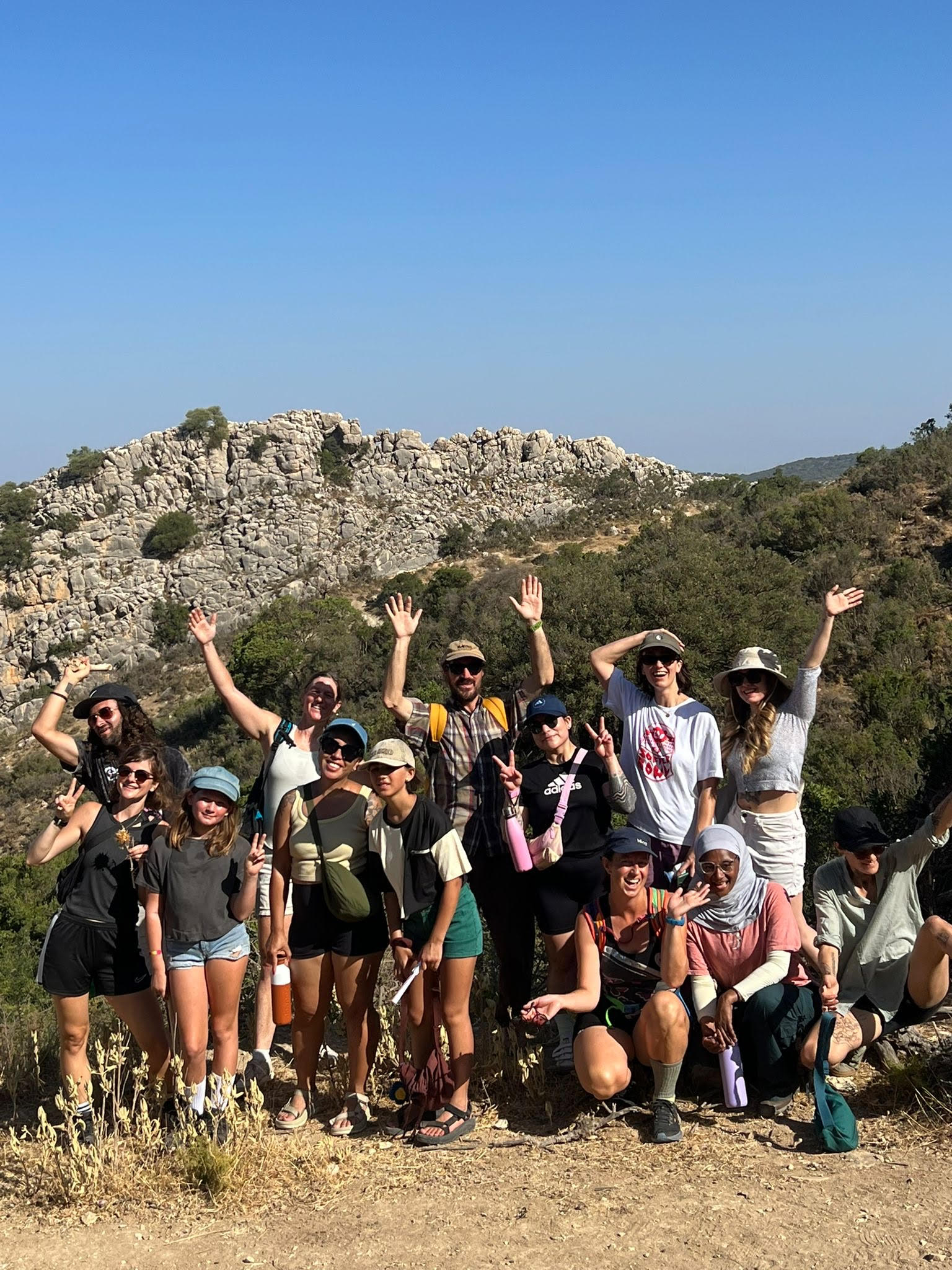 A group of campers cheering on a rocky mountain top near Las Navillas