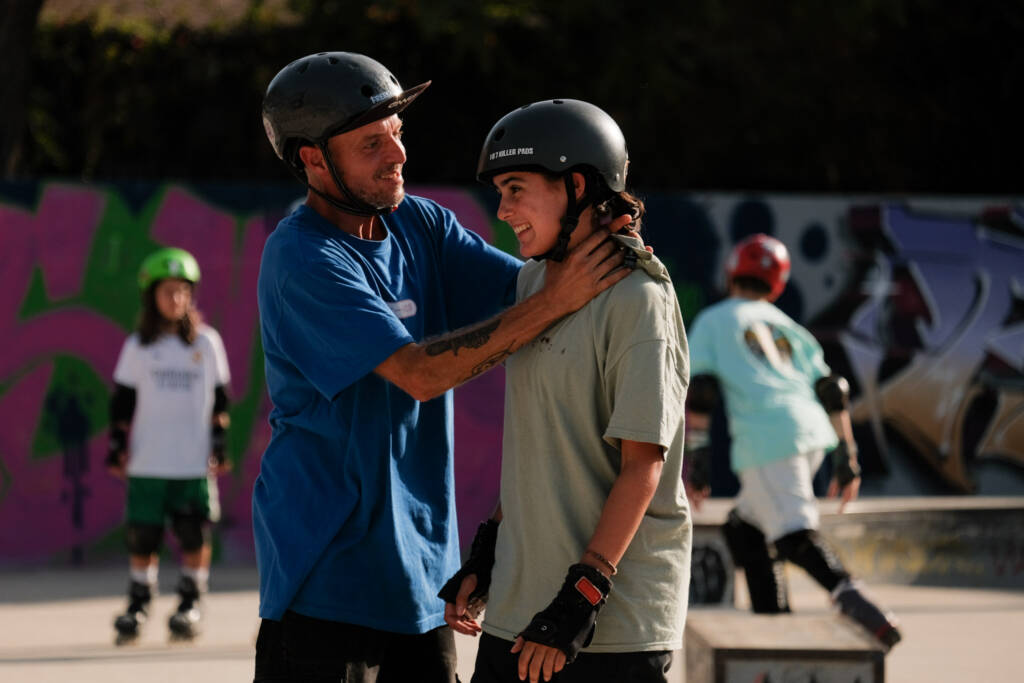 Coach adjusting a young skater’s helmet during a session