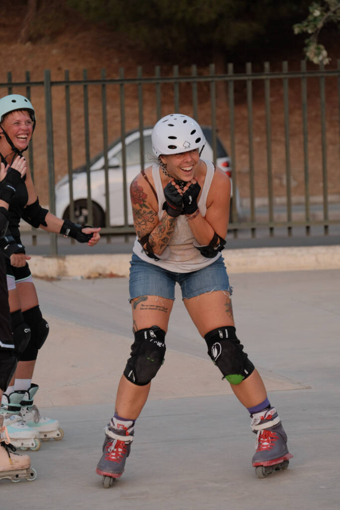 Tattooed skater in a white helmet beaming with excitement