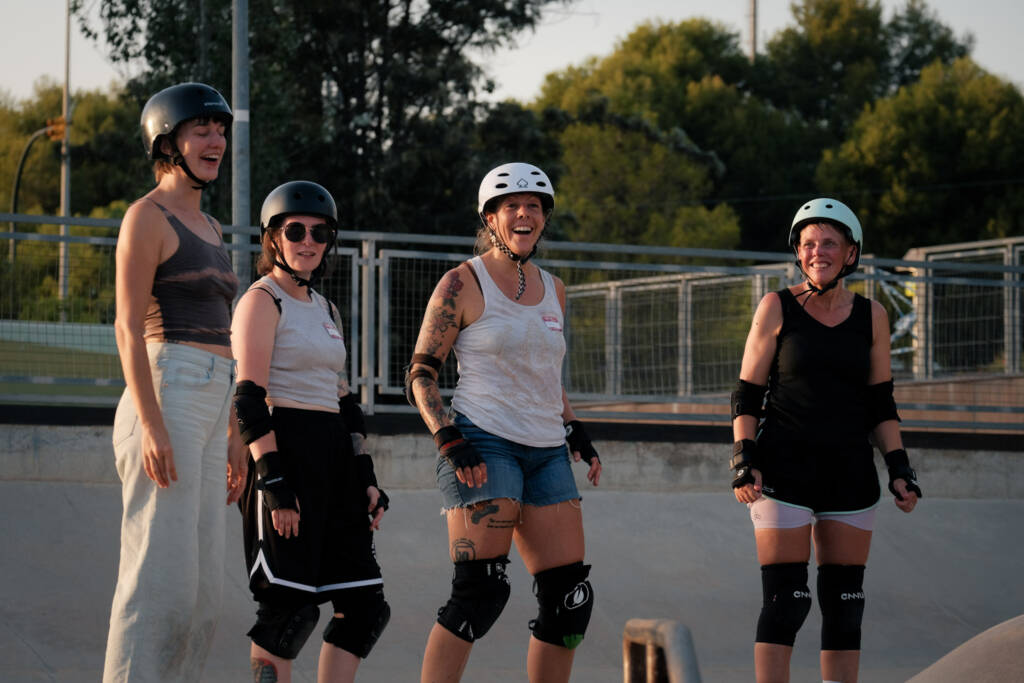 Four skaters laughing together at sunset in the skatepark