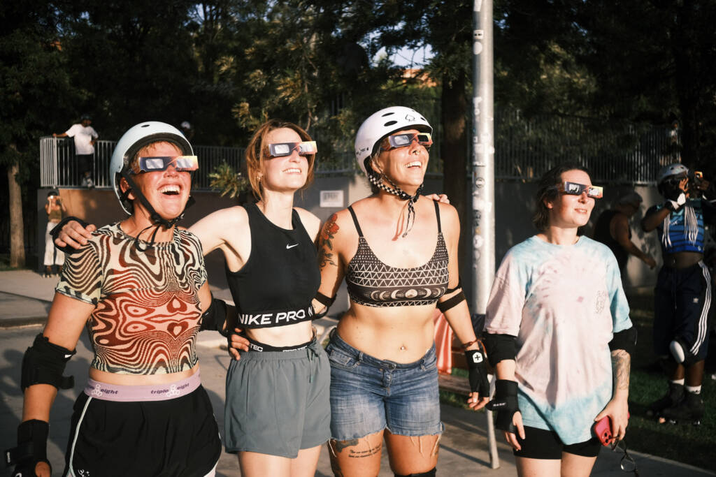Four skaters in eclipse glasses watching the sky together
